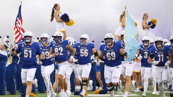 South Dakota State football players, including Logan Green (51) carrying the American flag and Quinten Christensen (69) carrying the South Dakota state flag, run on to the field at Dana J. Dykhouse Stadium prior to the Jackrabbits' Sept. 19, 2026, game against Youngstown State at Dana J. Dykhouse Stadium.