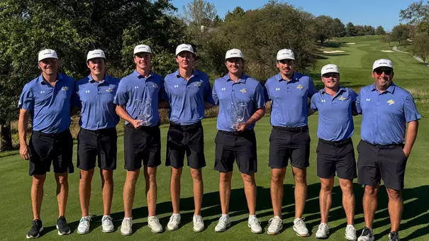 Men's golf team lined up for a team photo, with two athletes holding glass trophies