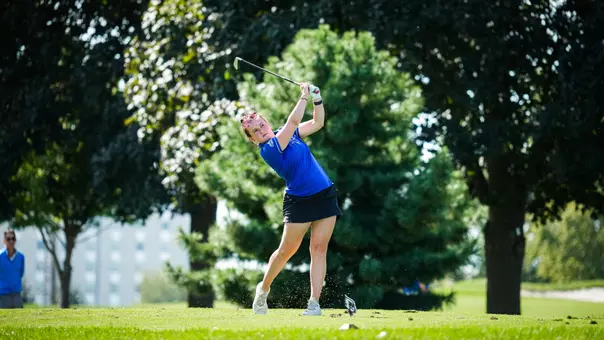 A golfer in a blue polo hits a shot