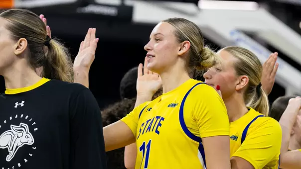 A women's basketball player, Hadley Thul, raises her hand toward a teammate for a high five
