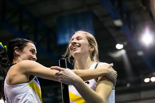 Two female track athletes hug after winning the 4x400m relay