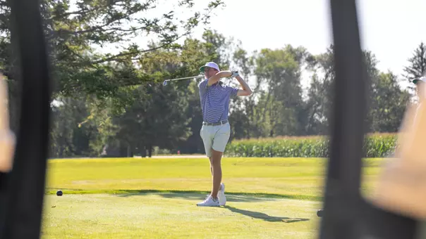 An SDSU men's golfer follows through on his swing during competition