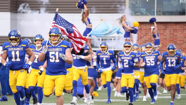 The South Dakota State football team, led by captains Joe Ollman (11) and Logan Green (51), runs on to the field prior to the start of the 2025 Hobo Day game against Northern Iowa at Dana J. Dykhouse Field.