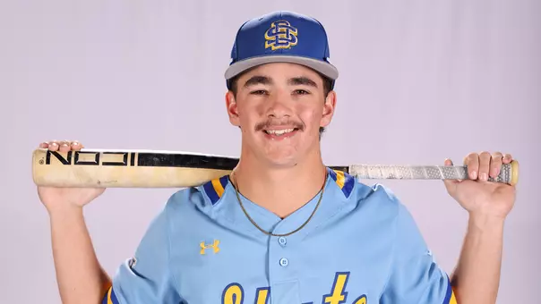 South Dakota State baseball player Carter Taylor poses for a photo in a light blue uniform with a bat resting on his shoulders behind his head during a photo day leading up to the 2026 season.