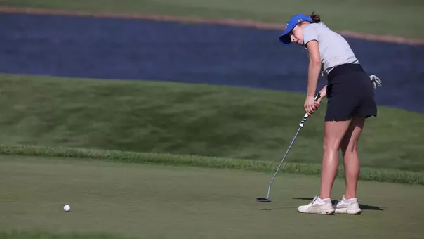 A women's golfer putts across the green during competition