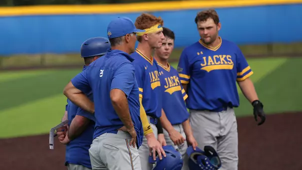 South Dakota State baseball coaches and players discuss strategy and watch an opposing pitcher warm up during a pitching change in exhibition action during the fall of 2025 at Erv Huether Field.
