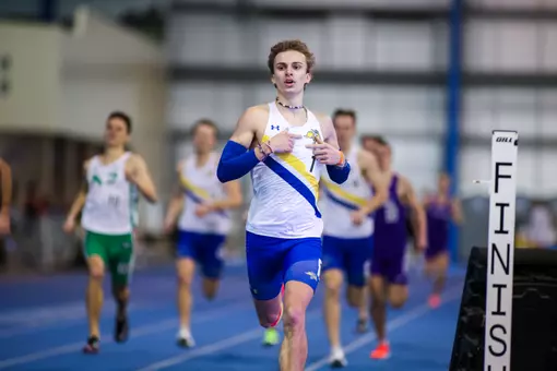 A male track runner finishes his race and begins to celebrate