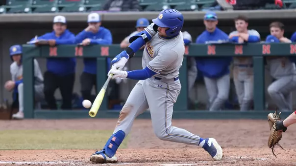 South Dakota State first baseman/designated hitter Dayton Franke makes solid contact while batting against Nebraska in action March 4, 2026. Franke is pictured swinging a yellow bat while wearing a gray uniform and blue batting helmet.