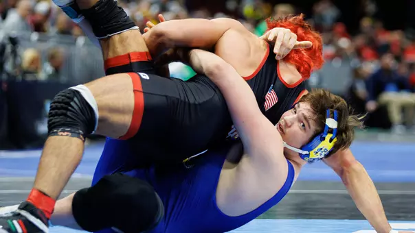 Luke Rasmussen in a blue singlet attempts to turn a wrestler in a black singlet.