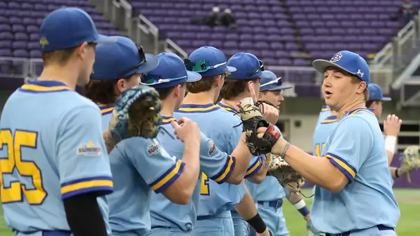 South Dakota State baseball players,including Luke Luskey in the foreground, tap gloves and shake hands during pregame warmups.