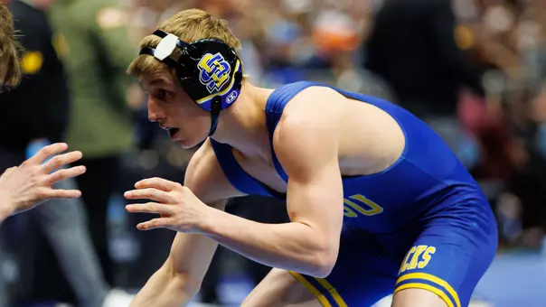 Brady Roark in a blue singlet stands in his stance during a wrestling match.