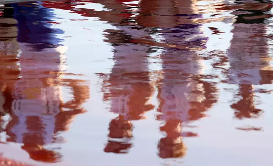 A photo of water on the track reflects men running past in a track and field race