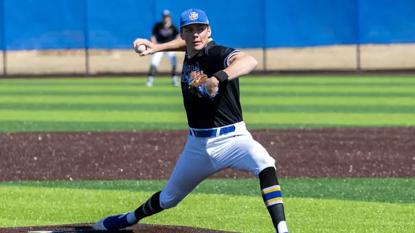 South Dakota State pitcher Sam Schlecht, wearing a black jersey, white pants and blue hat, fires a pitch to home plate in hom action against Dakota Wesleyan during the 2025 season.