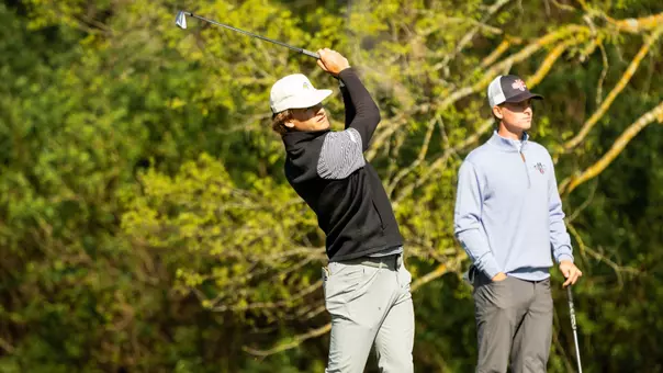 A men's golfer follows through on a swing during competition