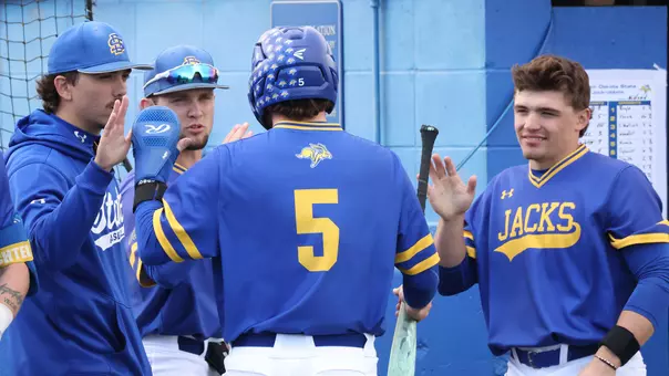 South Dakota State outfielder Luke Wroblewski (5) receives high-fives from teammates Will Kent, Brady Brown and Keagen Jirschele after scoring the first run of the game April 14 against Midland University.