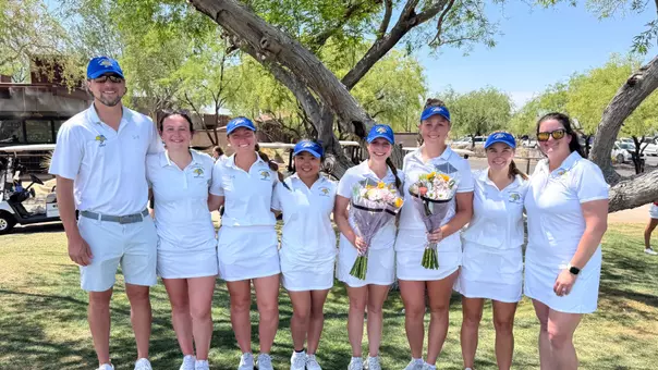 SDSU women's golfers and coaches pose for a team photo. Two players are holding flower bouquets.