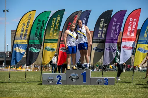 Two men in white and blue share the top of the podium together