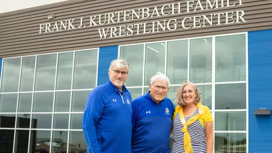 Frank J. Kurtenbach and family stand in front of the Frank J. Kurtenbach Wrestling Center at SDSU.
