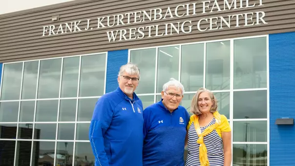 Frank J. Kurtenbach and family stand in front of the Frank J. Kurtenbach Wrestling Center at SDSU.