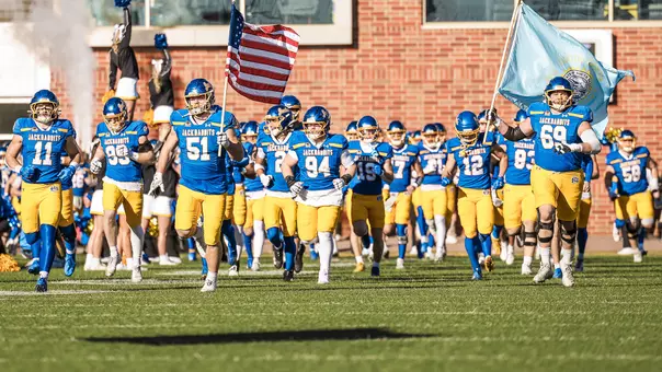 South Dakota State football players, some holding American and South Dakota state flags, run on to the field during their pregame entrance at Dana J. Dykhouse Stadium in a Nov. 15 game against Illinois State.