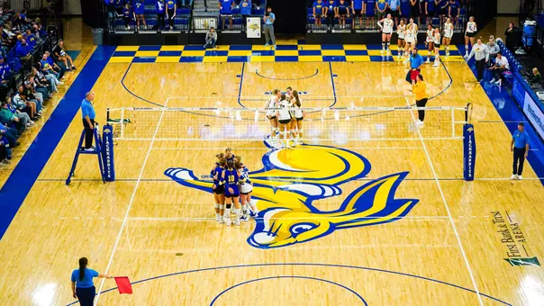 Two groups of players huddle during a volleyball match at First Bank & Trust Arena.