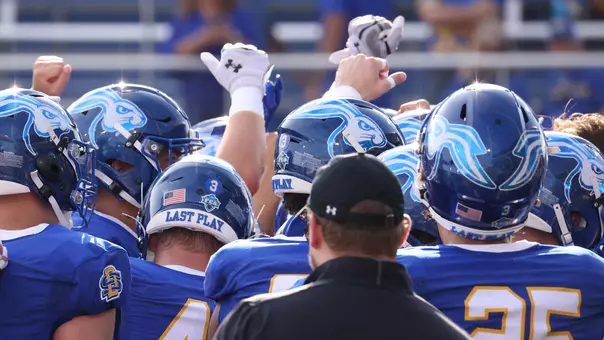 South Dakota State football players raise their hands in a huddle prior to their 2025 season-opening game against Sacramento State on Aug. 30, 2025, at Dana J. Dykhouse Stadium