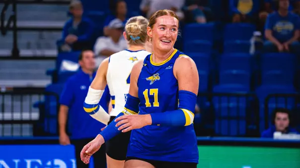 A volleyball player in blue smiles after a point during a match.