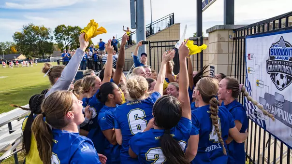 Soccer players celebrate beside the 2025 Summit League Women's Soccer Championship bracket board.