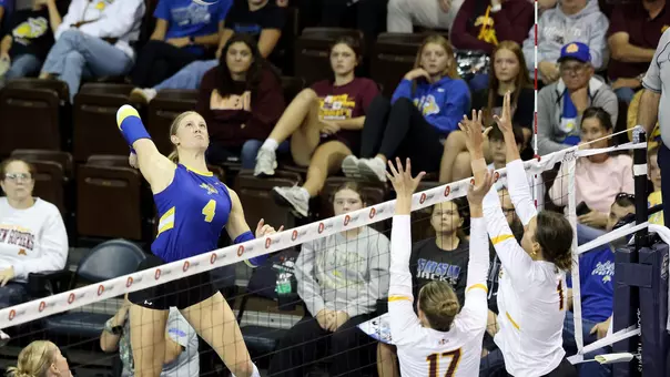 Hannah Klein in a blue uniform jumps to hit a ball.