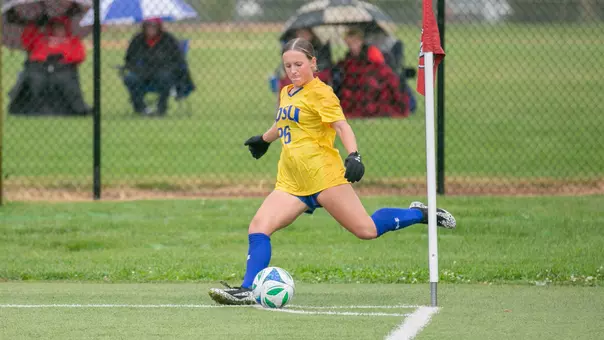 A photo of a woman in a yellow soccer uniform with blue shorts preparing to kick a ball on a corner kick opportunity
