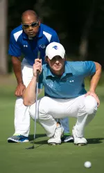 Head coach Clay White helps J.T. Harper line up a putt.