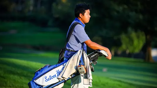 Golfer Wenliang Xie carries his golf club down the fairway.