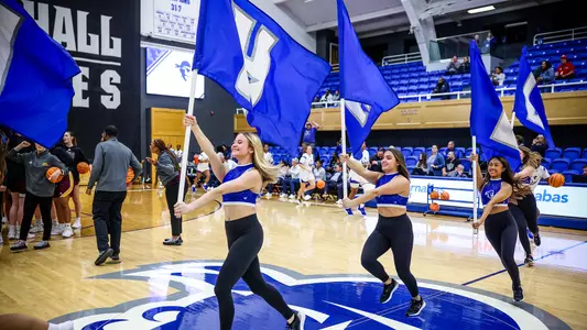 Cheerleaders introduce the Seton Hall WBB team by running with Seton Hall flags