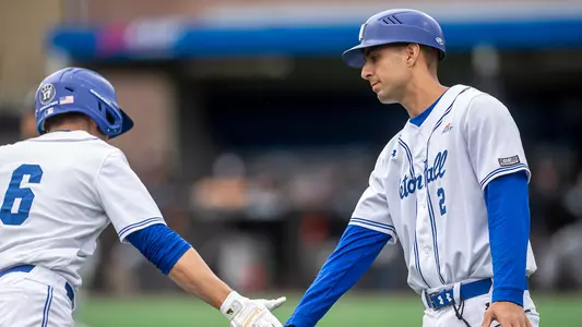 Associate head coach Giuseppe Papaccio high fives Max Viera after a home run against Manhattan