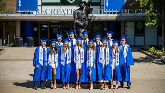 Graduating members of the swimming and diving team pose for a photo in their caps & gowns