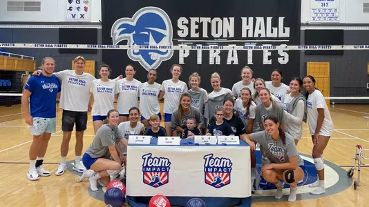The Seton Hall volleyball team poses with members of Team IMPACT