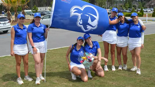 Seton Hall women's golf team poses next to the Pirates' flag at the 2025 BIG EAST Championship