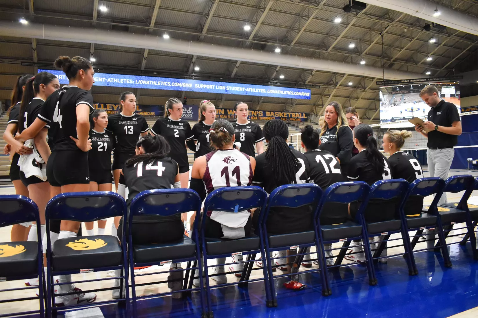 Head Coach Brittany Harry talks to her team in between sets.