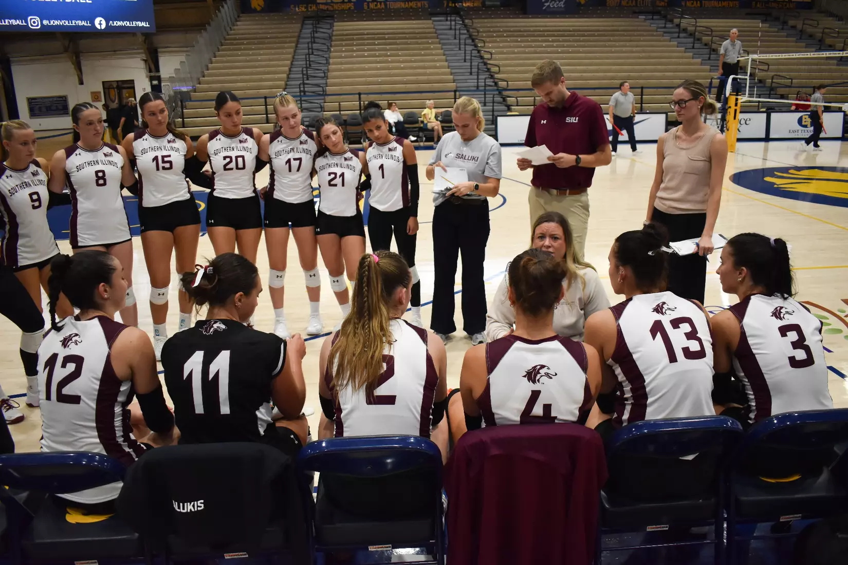Head Coach Brittany Harry kneels down and talks with her team during a timeout.