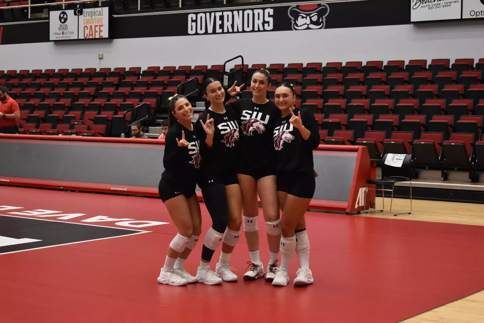 Members of the team smile and hold up dog ears.