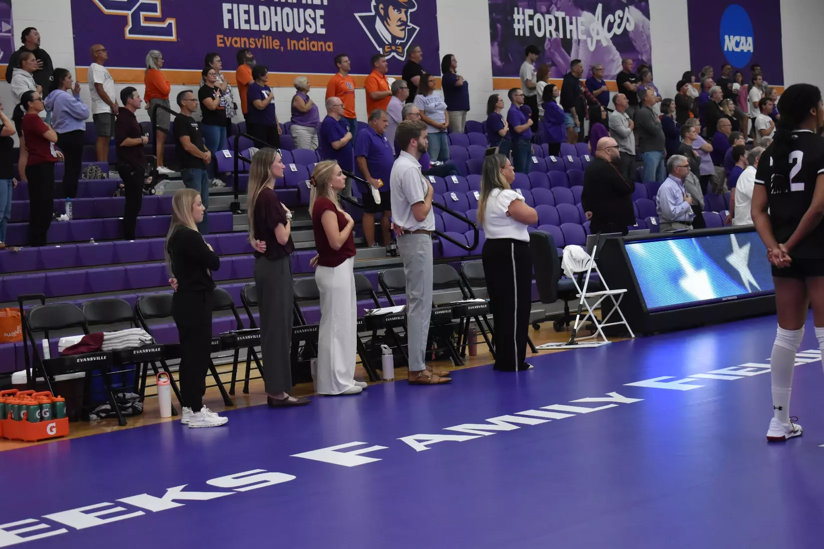 The coaching staff stands next to each other during the National Anthem.