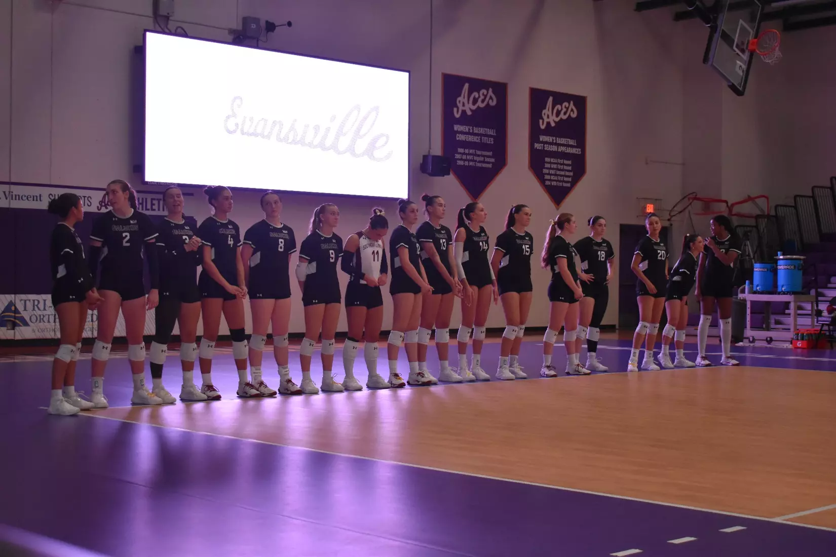 The team stands together in the dark during opposing introductions.