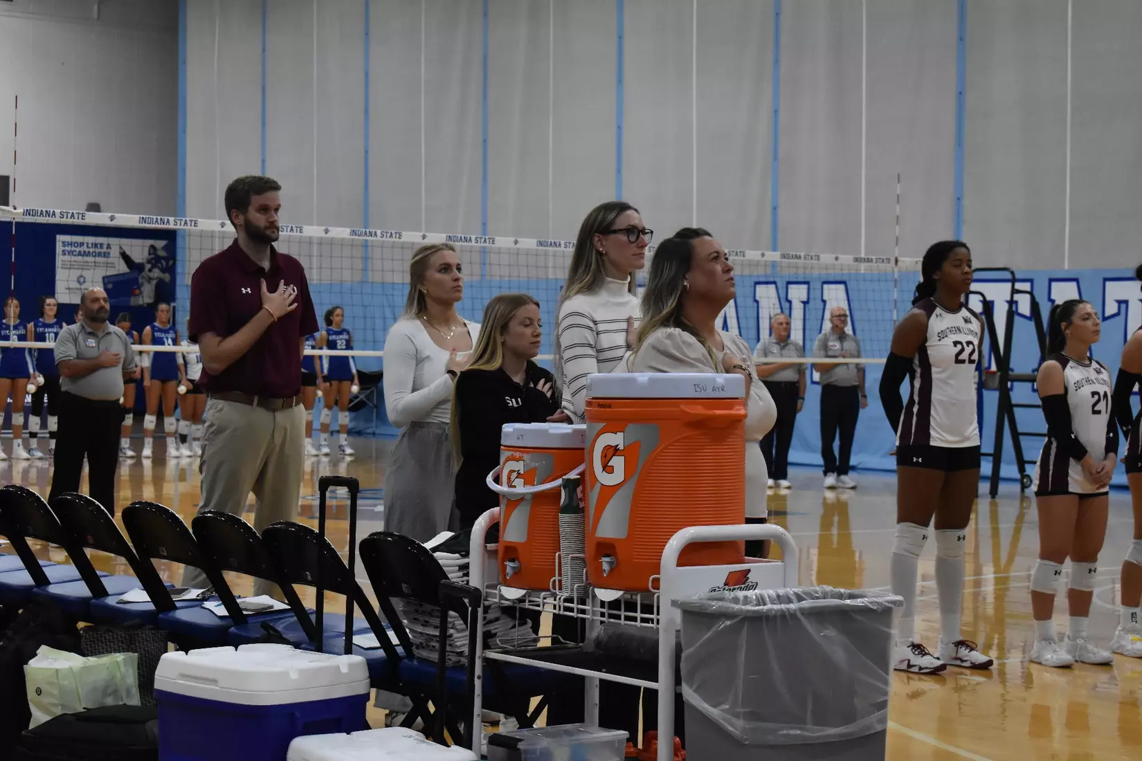 The coaching staff stands next to each other during the national anthem.