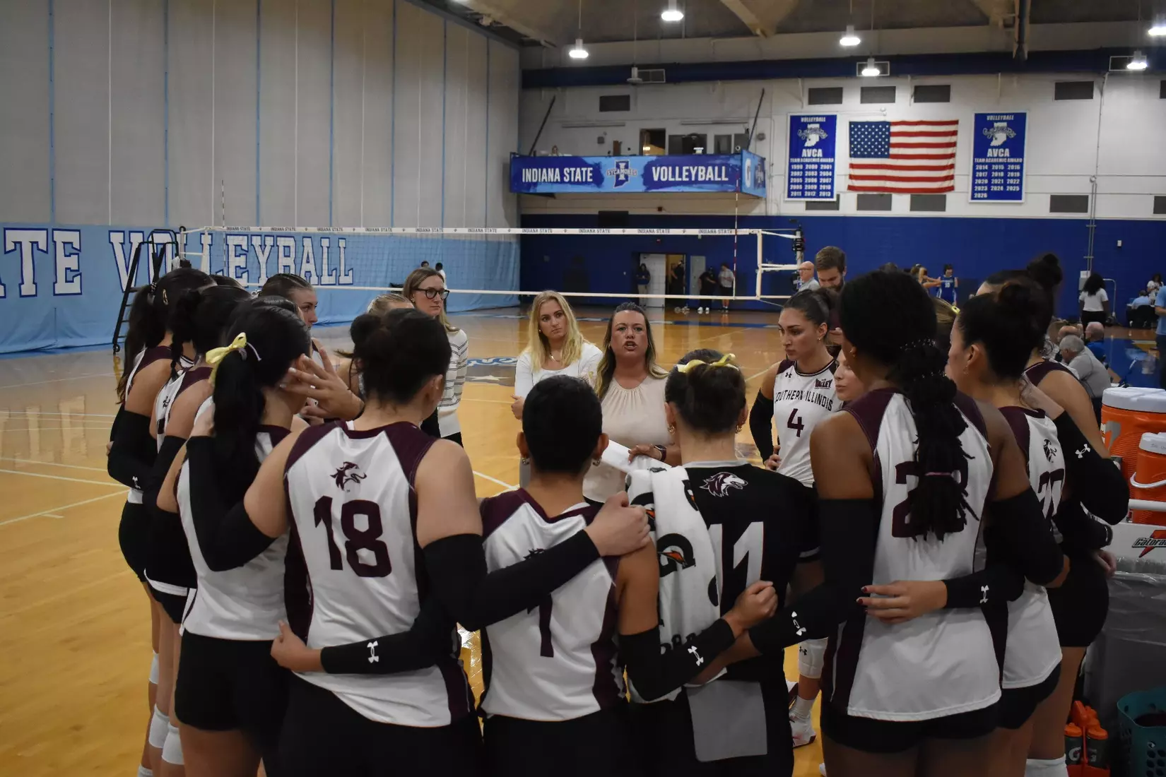 Head Coach Brittany Harry talks to her team in between sets.