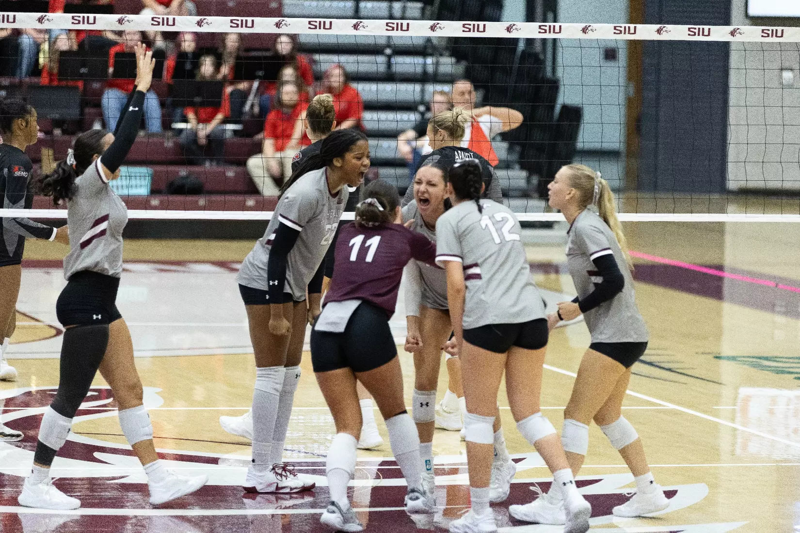 The team on the court huddles and celebrates after a point.