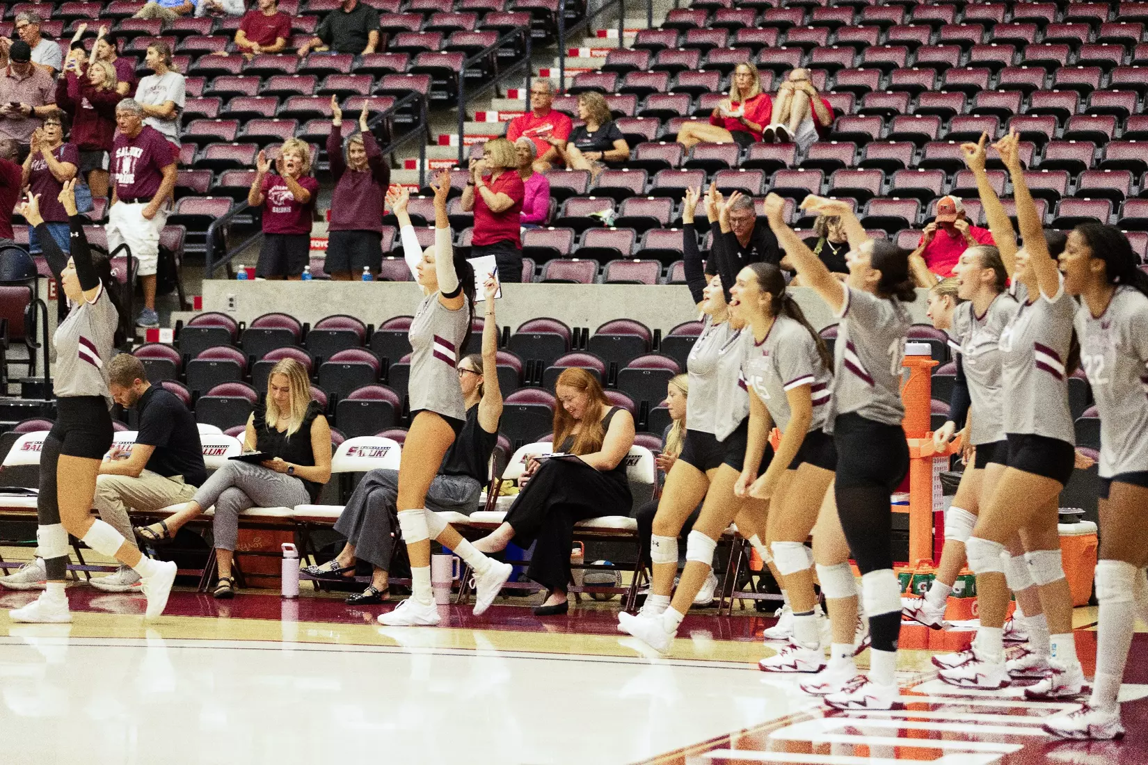 The bench throws their hands up and celebrates after a point.