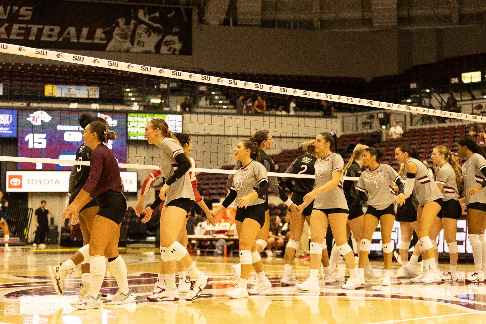 The team high fives SEMO under the net after the match.