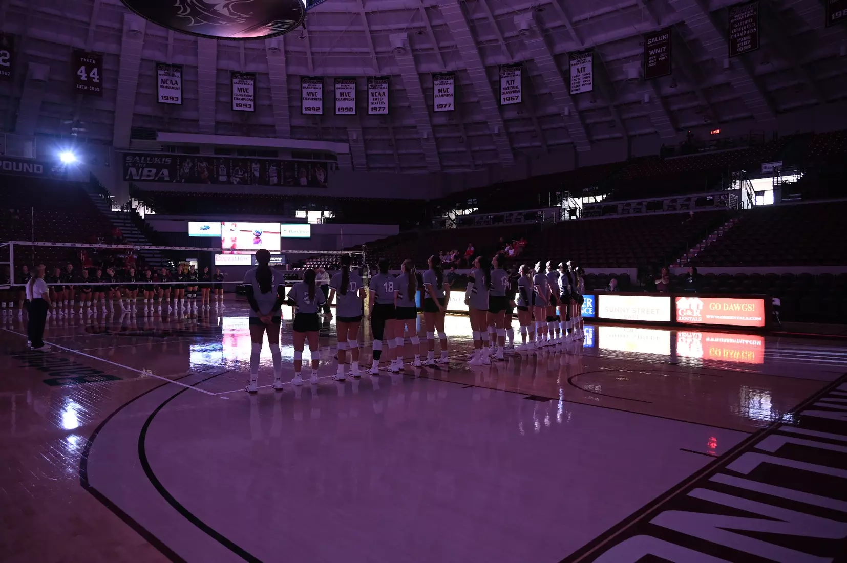 The team stands in the dark as they watch their hype video.