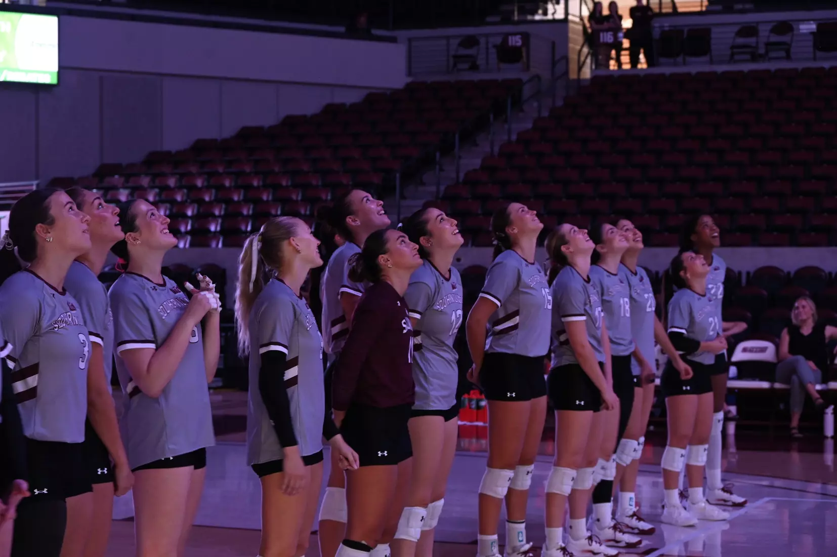 The team stands and watches their hype video.