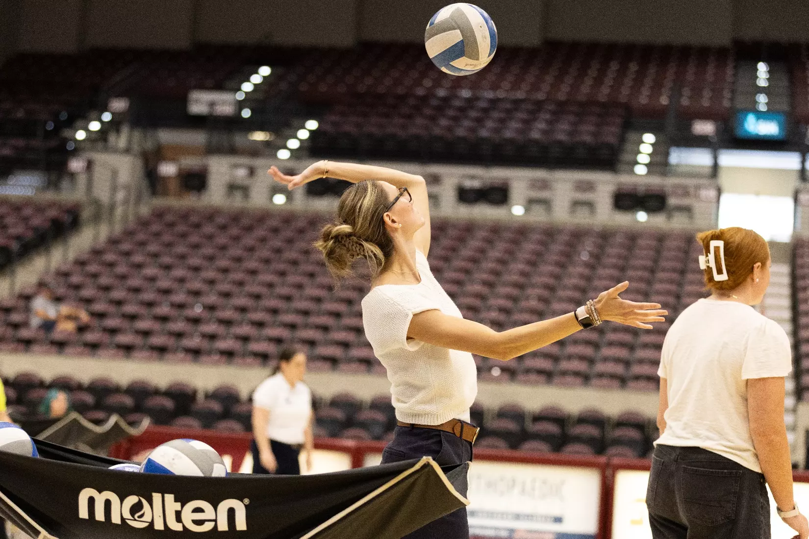 Assistant Coach Bryleigh Buchanan hits a ball in warmups.